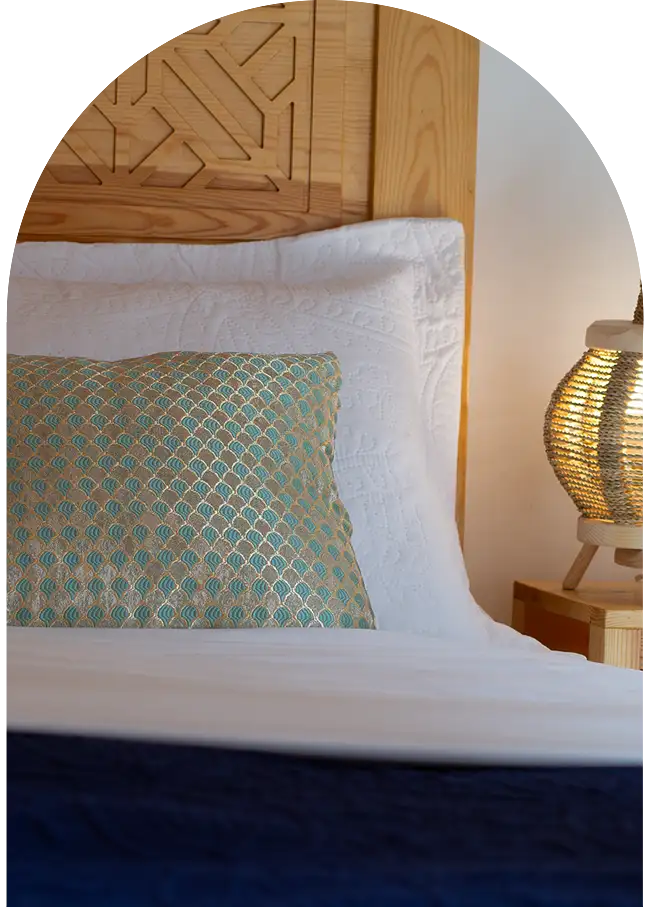 Moroccan carved wooden bed with neatly arranged linens in a riad bedroom in Essaouira