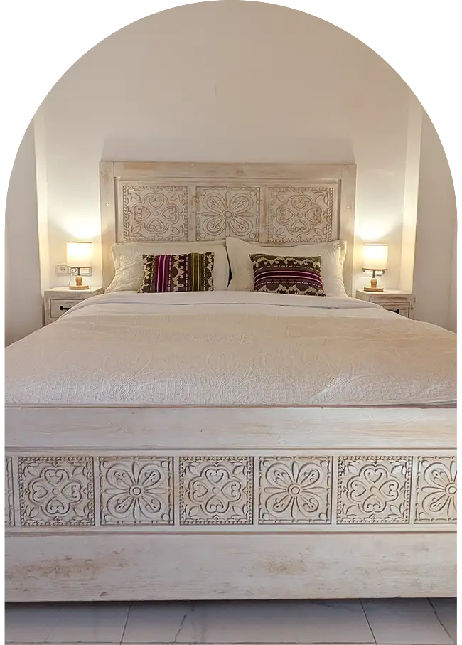 Double carved wooden bed with elegant linens in a riad in Essaouira