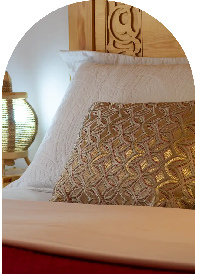Moroccan carved wooden bed with neatly arranged linens in a riad bedroom in Essaouira